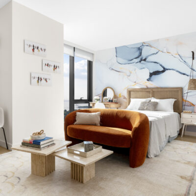 A children's bedroom with full sized bed, floor to ceiling windows, and feature wall detailed in a marble texture