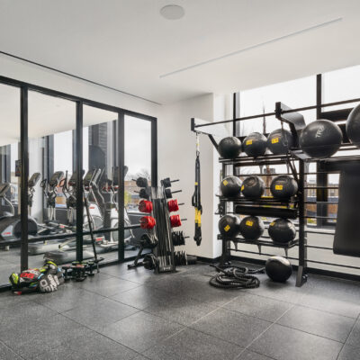 A modern gym and fitness center with black floor, free weights, machines, stretching equipment, and floor to ceiling mirrors
