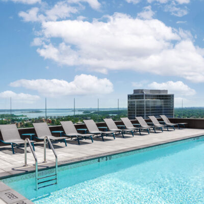 A rooftop pool deck at a high rise luxury apartment building with chaise lounges and tables overlooking the Long Island Sound