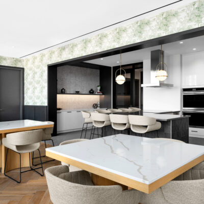A modern lounge with shared kitchen space, with white topped marble tables for entertaining