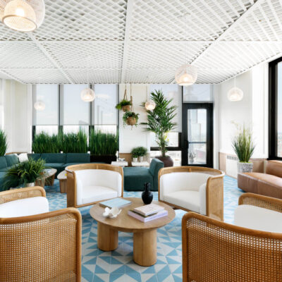 A relaxed lounge area featuring cozy seating and a terraced ceiling, with large plants and floor to ceiling windows